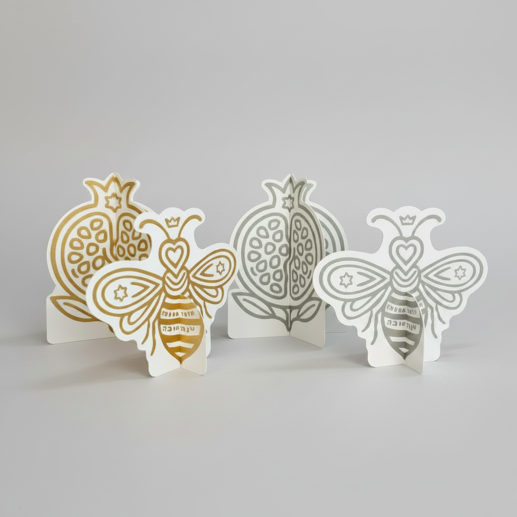 Silver and gold 3D bee and pomegranate decorations for a Rosh Hashanah table