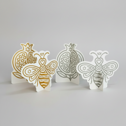 Silver and gold 3D bee and pomegranate decorations for a Rosh Hashanah table