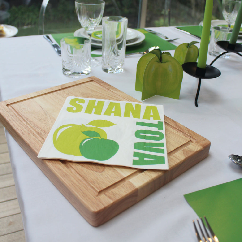 wooden chopping board with green apple serviettes on a table setting 